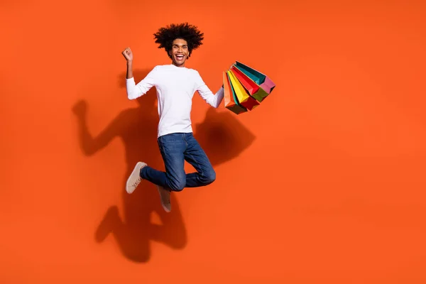 Foto av förvånad lycklig kille bära vit skjorta hoppa höga stigande fynd tomt utrymme isolerad orange färg bakgrund — Stockfoto