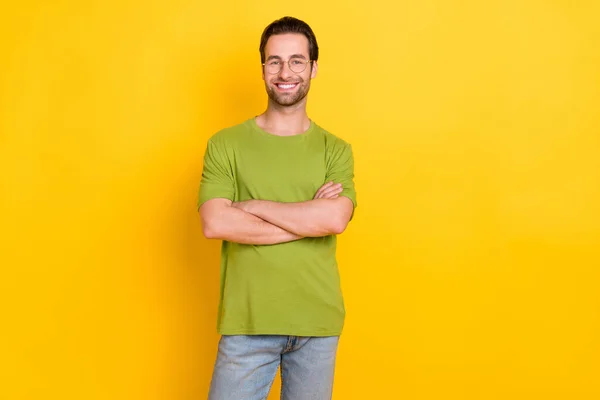 Zdjęcie inteligentnej brody młody facet skrzyżowane ramiona nosić okulary zielony t-shirt odizolowany na żółtym tle kolor — Zdjęcie stockowe