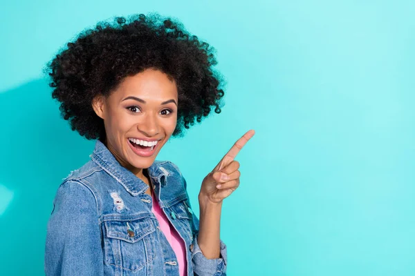 Photo de jolie jeune femme excitée habillée veste en denim pointant l'espace vide isolé fond de couleur sarcelle — Photo