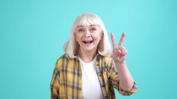 Funky mormor göra v-tecken helg isolerad akvamarin färg bakgrund — Stockvideo