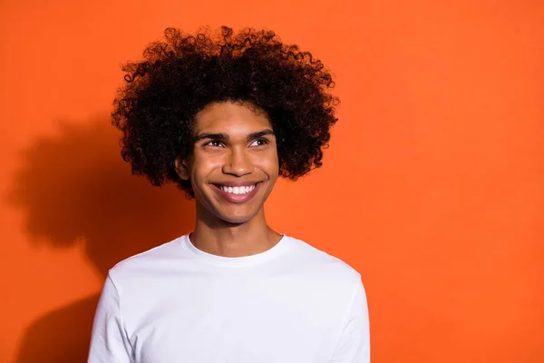 Foto de chico lindo de ensueño vestido camisa blanca sonriendo buscando espacio vacío aislado color naranja fondo —  Fotos de Stock