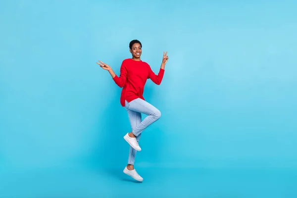 Full size photo of jumping nonbinary girl showing v-sign say hello meet friends isolated on blue color background — Stock fotografie