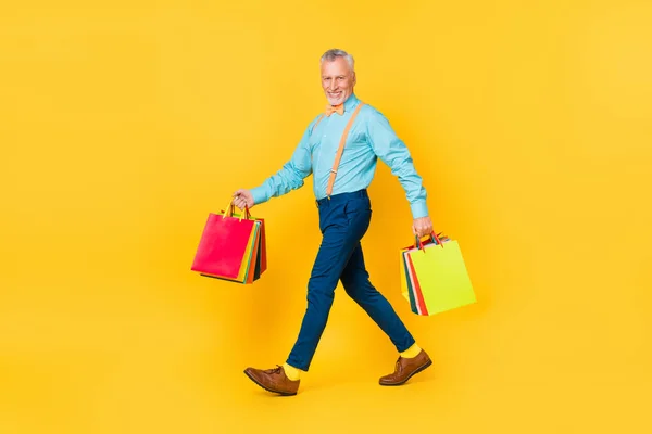 照片上，甜美而快乐的退休人员身穿茶色衬衫领带，手里拿着便宜货，背景是黄褐色的 — 图库照片