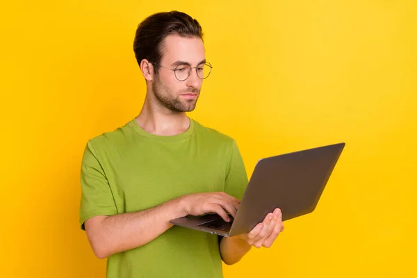 严格意义上的胡子千年虫型笔记本电脑的照片，带着眼镜绿色T恤，与黄色背景隔离 — 图库照片