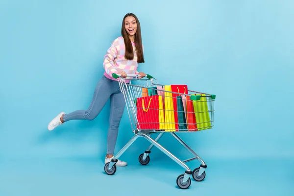 Photo of crazy positive lady enjoy retail hold cart Have fun kopás pulóver farmer tornacipő elszigetelt kék szín háttér — Stock Fotó