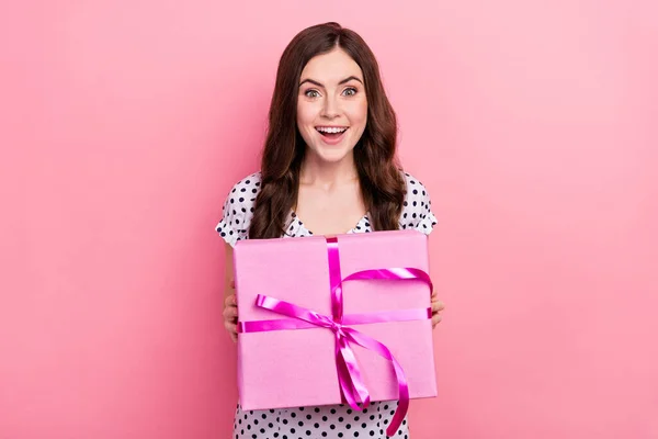 Фото фанки взволнованной дамы одеты пунктирные платье с большой подарок коробка улыбается изолированный розовый цвет фона — стоковое фото