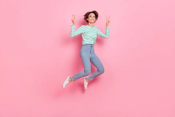 Teljes hossz testméret kilátás vonzó vidám lány vicces lány jumping mutatja v-jel elszigetelt rózsaszín pasztell szín háttér — Stock Fotó