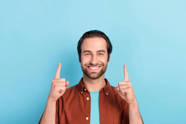 Фотографія доброзичливого веселого хлопця, який вказує на копійку, рекламує просування продукту ізольовано на фоні синього кольору — стокове фото