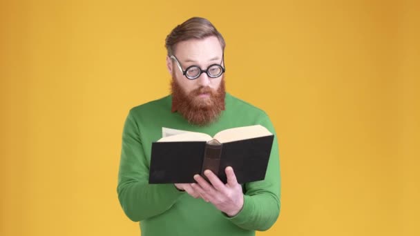 Geeky ชายอ่านหนังสือค้นพบข้อเท็จจริงที่ยอดเยี่ยมแยกพื้นหลังสีสว่าง — วีดีโอสต็อก