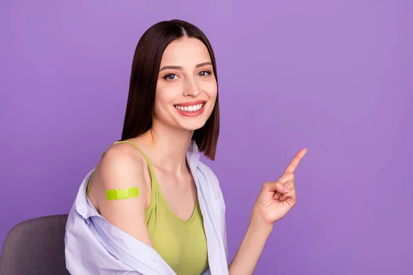 Foto de la optimista morena milenaria dama indican espacio vacío hizo la vacunación usar camisa superior aislado sobre fondo púrpura —  Fotos de Stock