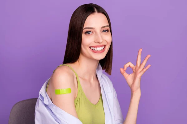 Foto de dulce morena joven show okey hizo la vacunación usar camisa superior aislado sobre fondo púrpura —  Fotos de Stock