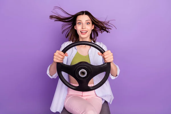 照片上，快乐的黑发女士驾驶着紧身衣牛仔裤，上衣与紫色背景隔离 — 图库照片