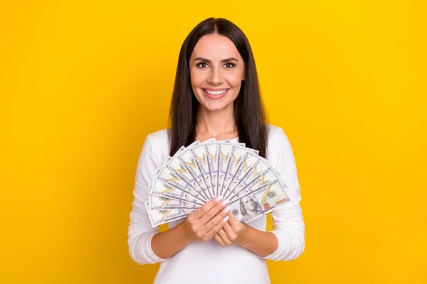 Fotografie mladé veselé hezká žena bohatá držet hotovost úspory zisk izolované přes žluté barvy pozadí — Stock fotografie