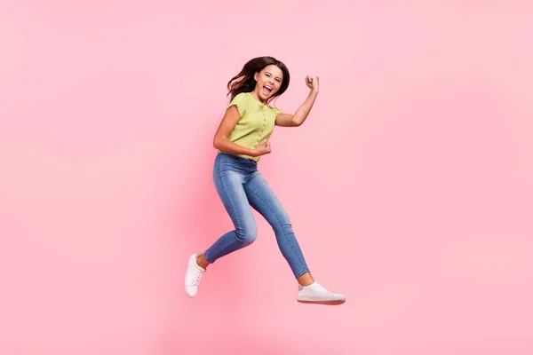 Foto de señora sorprendida salto levante los puños regocijarse grito meta desgaste verde superior jeans calzado aislado de color rosa fondo —  Fotos de Stock
