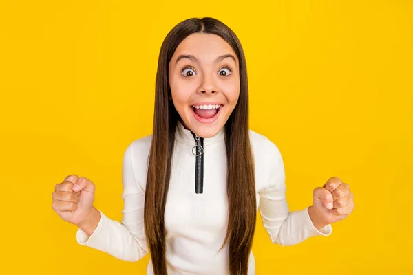 Foto van onder de indruk gelukkige tiener meisje gekleed witte rits shirt rijzende vuisten glimlachen geïsoleerde gele kleur achtergrond — Stockfoto