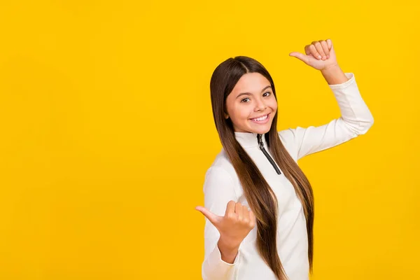 Foto de linda estudiante emocionada chica usar camisa blanca con cremallera sonriendo apuntando hacia atrás pulgares espacio vacío aislado color amarillo fondo — Foto de Stock