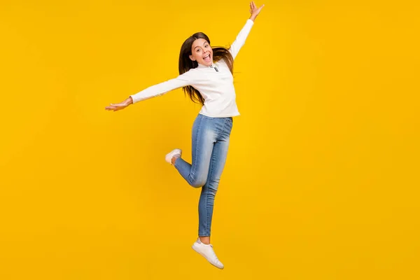 Foto de cuerpo completo de linda morena niña pequeña salto desgaste jersey jeans calzado aislado sobre fondo de color amarillo —  Fotos de Stock