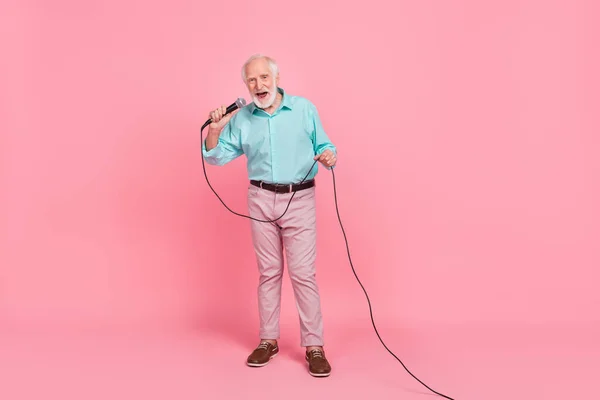 Volledige lengte foto van koele man van middelbare leeftijd zingen microfoon uit te voeren vintage melodie geïsoleerde pastel kleur achtergrond — Stockfoto