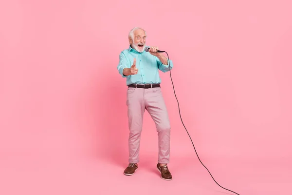 Full size foto van koele middelbare leeftijd man zingen mic point hey je index vinger geïsoleerde pastel kleur achtergrond — Stockfoto
