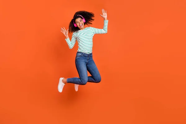 Foto em tamanho completo de salto milenar senhora ouvir música usar fones de ouvido camisa jeans sapatos isolados no fundo laranja — Fotografia de Stock