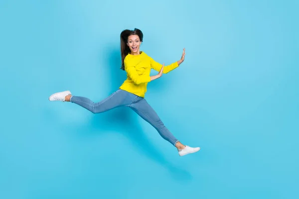 Foto de cuerpo entero de la joven morena impresionada mujer salto usar camisa jeans zapatillas aisladas sobre fondo azul — Foto de Stock