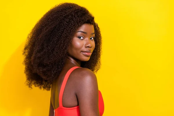 Fotografie lesklé okouzlující africká dáma oblečená červená sexy oblečení usmívající se prázdný prostor izolované žluté barvy pozadí — Stock fotografie