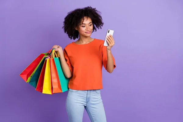 Foto av vackra bruna hår flicka chatta i telefon gå shopping köpa casual kläder isolerad på violett färg bakgrund — Stockfoto