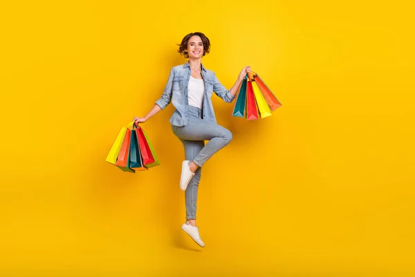 Teljes test profil oldal fotó fiatal nő ugrás bevásárlóközpont kedvezmény elszigetelt sárga szín háttér — Stock Fotó