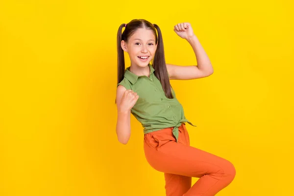 Foto van vrij gelukkig tiener meisje gekleed groene top lopen rijzende vuisten glimlachen geïsoleerde gele kleur achtergrond — Stockfoto