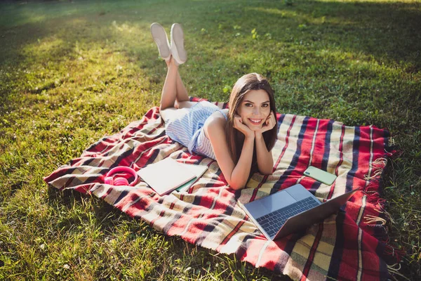 Portrét atraktivní veselá dívka ležící na obálce pomocí notebooku tráví volný čas zábava na čerstvém vzduchu venku — Stock fotografie