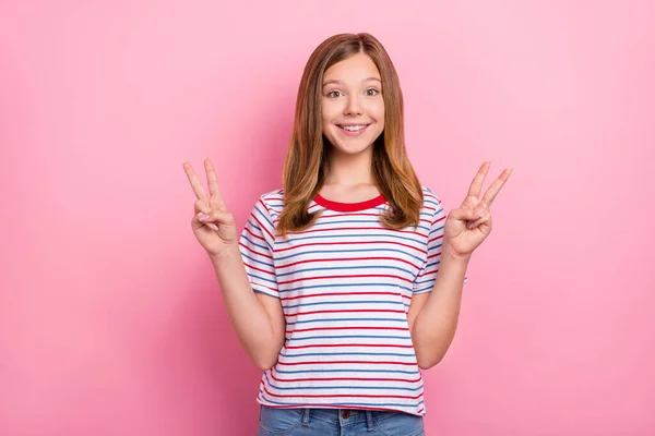 かなり小さな茶色の髪型の女の子の写真ショーvサインはピンクの色の背景に隔離された赤いTシャツを着用 — ストック写真