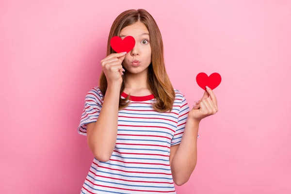 Photo de impressionnée petite fille brune coiffure tenir coeur coup baiser porter t-shirt rayé isolé sur fond de couleur rose — Photo