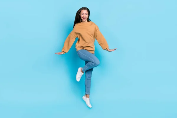 Foto de longitud completa de fresco joven morena dama salto usar suéter jeans zapatos aislados sobre fondo azul —  Fotos de Stock
