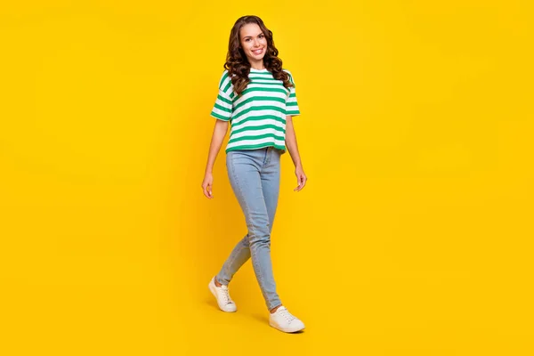Полная длина фото милой брюнетки волнистый Millennial леди пойти носить футболки джинсы обувь изолированы на желтом фоне цвета — стоковое фото