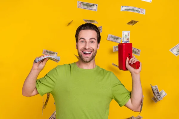 Photo of cool beard young guy hold money gun wear green t-shirt isolated on yellow color background — Stock Photo, Image