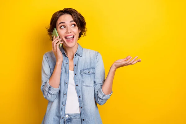 Photo de jeune femme gaie conversation de bonne humeur téléphone cellulaire regarder espace vide isolé sur fond de couleur jaune — Photo