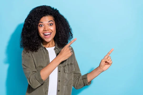 Φωτογραφία του νεαρού ενθουσιασμένοι υποστηρικτής κορίτσι της Αφρικής δείχνουν δάχτυλα κενό χώρο πώληση διαφημίσεων promo απομονώνονται σε μπλε χρώμα φόντο — Φωτογραφία Αρχείου