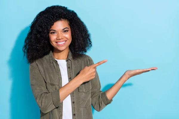 Fénykép a fiatal csinos afrikai lány jelzi ujj termék promo reklámok ajánlat elszigetelt felett kék színű háttér — Stock Fotó