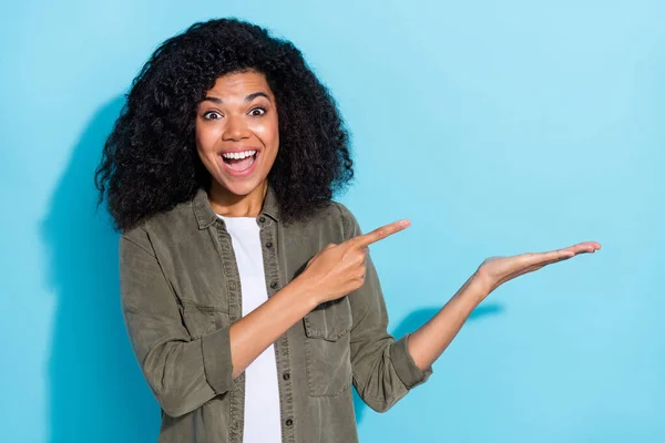 Foto de joven mujer africana emocionado indican dedo anuncian sugieren descuento aislado sobre fondo de color azul —  Fotos de Stock