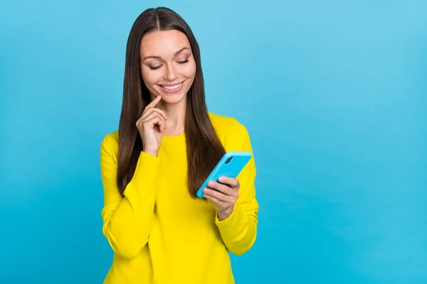 Фото милой юной брюнетки леди смотреть телефон носить желтую рубашку изолированы на синем фоне — стоковое фото