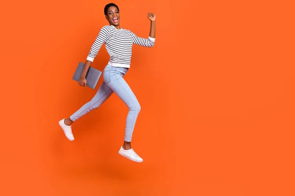 Foto de divertido apresurándose señora Butch vestido suéter saltando sosteniendo gadget espacio vacío aislado color naranja fondo —  Fotos de Stock