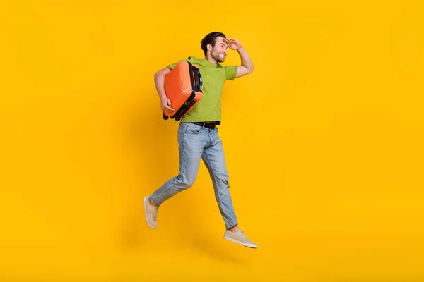 Volledige lengte profiel zijkant foto van jonge man hold bag kijken lege ruimte vliegen geïsoleerd over gele kleur achtergrond — Stockfoto