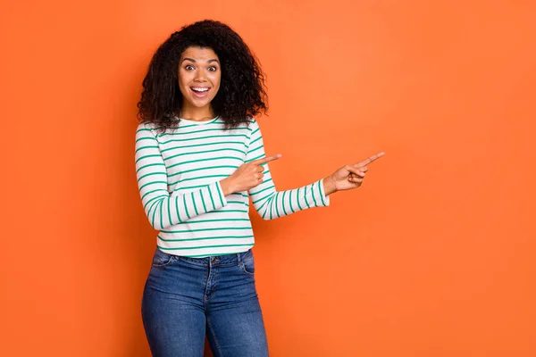 Фотография впечатляет объем волос миллениум леди указывают на промо носить рубашку джинсы изолированы на фоне оранжевого цвета — стоковое фото