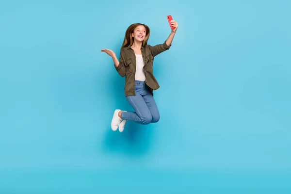 Full storlek foto av vackra tonåring flicka hoppa tal på kameran bloggare hålla handen annonsera isolerad på blå färg bakgrund — Stockfoto