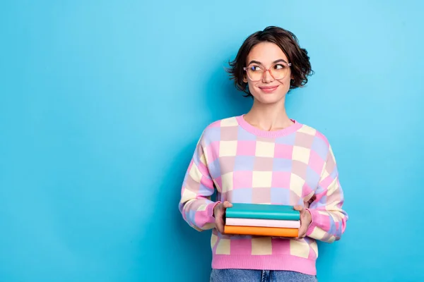 Foto de inteligente jovem morena senhora segurar livro olhar promo desgaste eyewear camisola quadriculada isolado no fundo azul — Fotografia de Stock