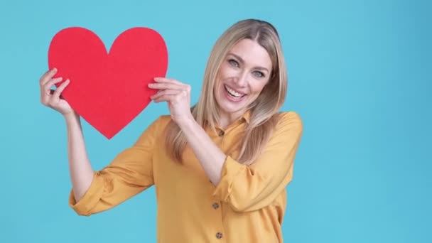 Hübsche Dame zeigen große 14 Februar Geschenk Herz isoliert blaue Farbe Hintergrund — Stockvideo