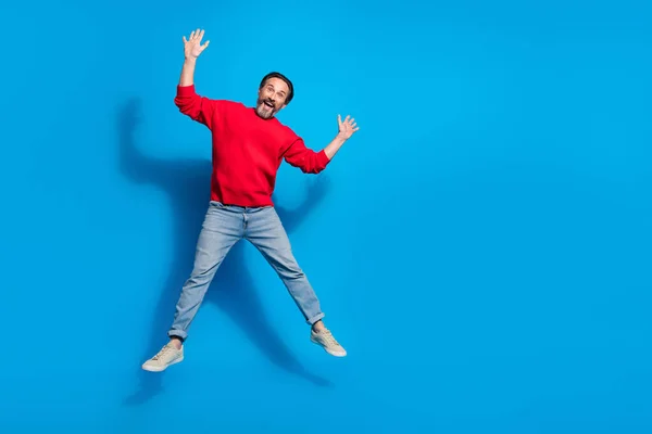 Foto em tamanho completo de animado louco alegre cara brincando em torno de saltar para cima relaxar em férias isoladas no fundo de cor azul — Fotografia de Stock