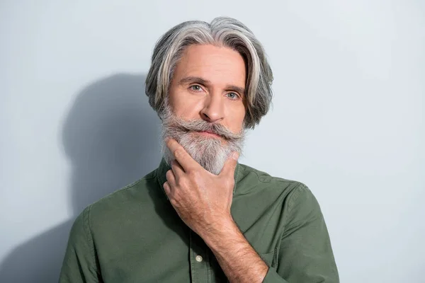 Portrett av velstelt, velstelt, gråhåret mann som berører skjegg og bestemmer seg for å være isolert over grå pastellfarget bakgrunn – stockfoto