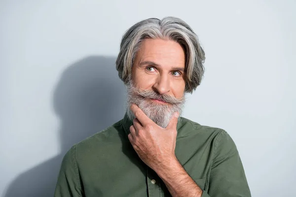 Portrait d'un homme attrayant et bien soigné aux cheveux gris, touchant la barbe, prenant une décision isolée sur un fond gris de couleur pastel — Photo