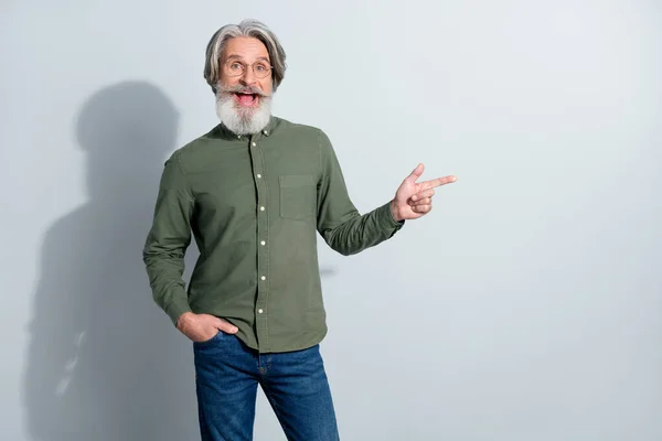 Porträtt av attraktiva glada förvånad gråhårig man visar kopia utrymme ny annons isolerad över grå pastell färg bakgrund — Stockfoto